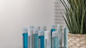 Ein Regal mit blauen und weißen Flaschen, ein gewebter Korb mit einer Pflanze und zwei gerahmte Bilder an der Wand.