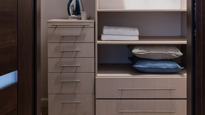 Ein begehbarer Kleiderschrank mit offenen Regalen, Kleiderstangen und Schubladen.