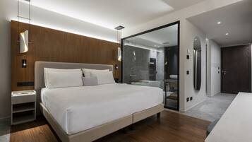 A modern bedroom with a large bed, bedside tables, a mirror, and a walk-in closet.