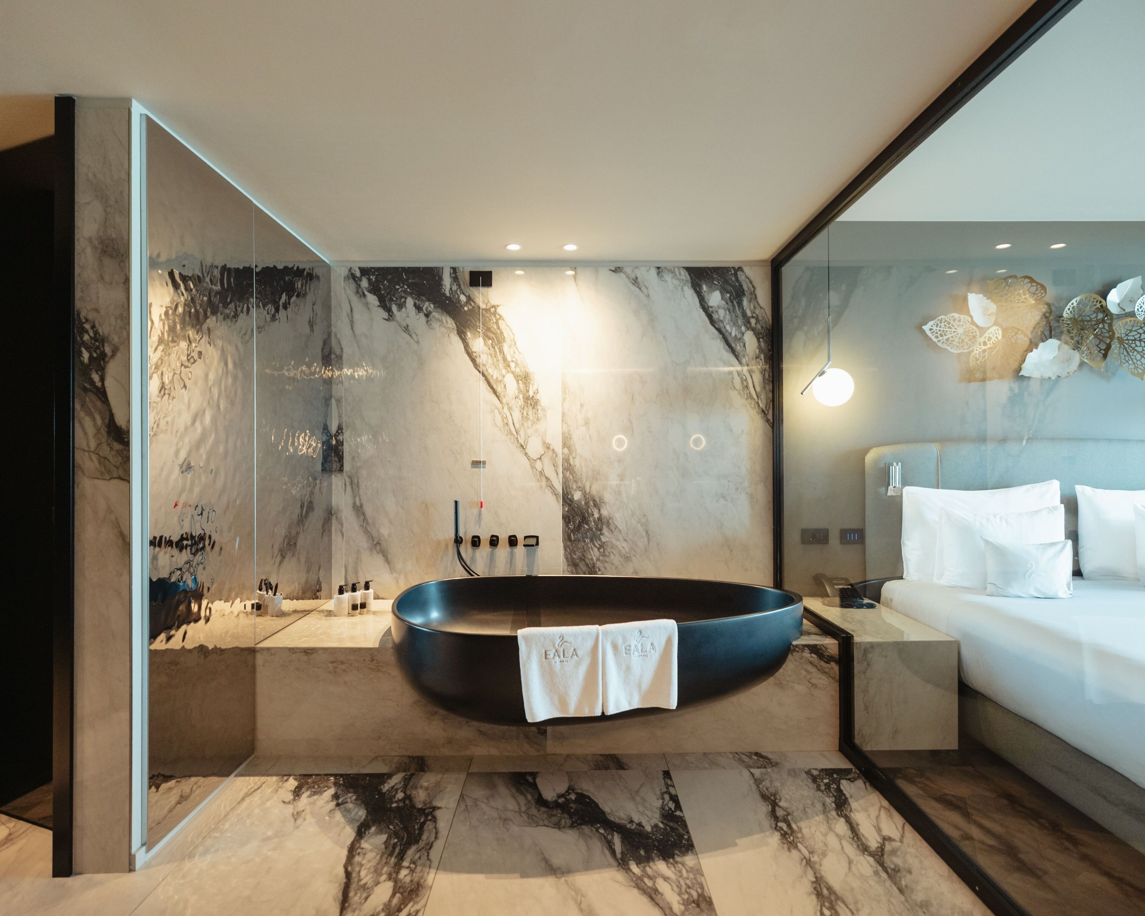 Ein modernes Badezimmer mit freistehender Badewanne, Marmorwänden und einer Duschkabine aus Glas.