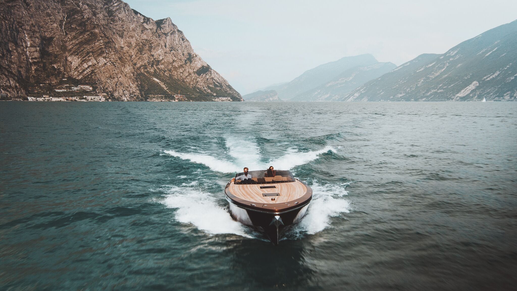A boat moving through a body of water with mountainous terrain in the background.