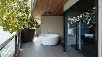 A modern bathroom with a freestanding bathtub, a potted plant, and a glass shower enclosure.
