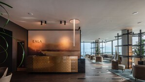 A modern reception area with a reception desk, seating, and a large window offering a view. - EALA My Lakeside Dream – Adults Only (Limone sul Garda)