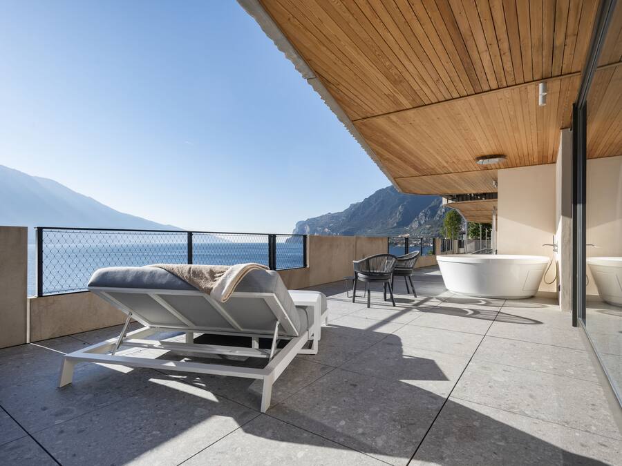 Een balkon met een lounge stoel, een kleine tafel en een bad.