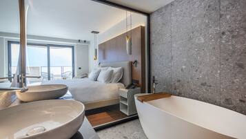 A modern bathroom with a large bathtub, two bowls, a bed with a view, and a large mirror.