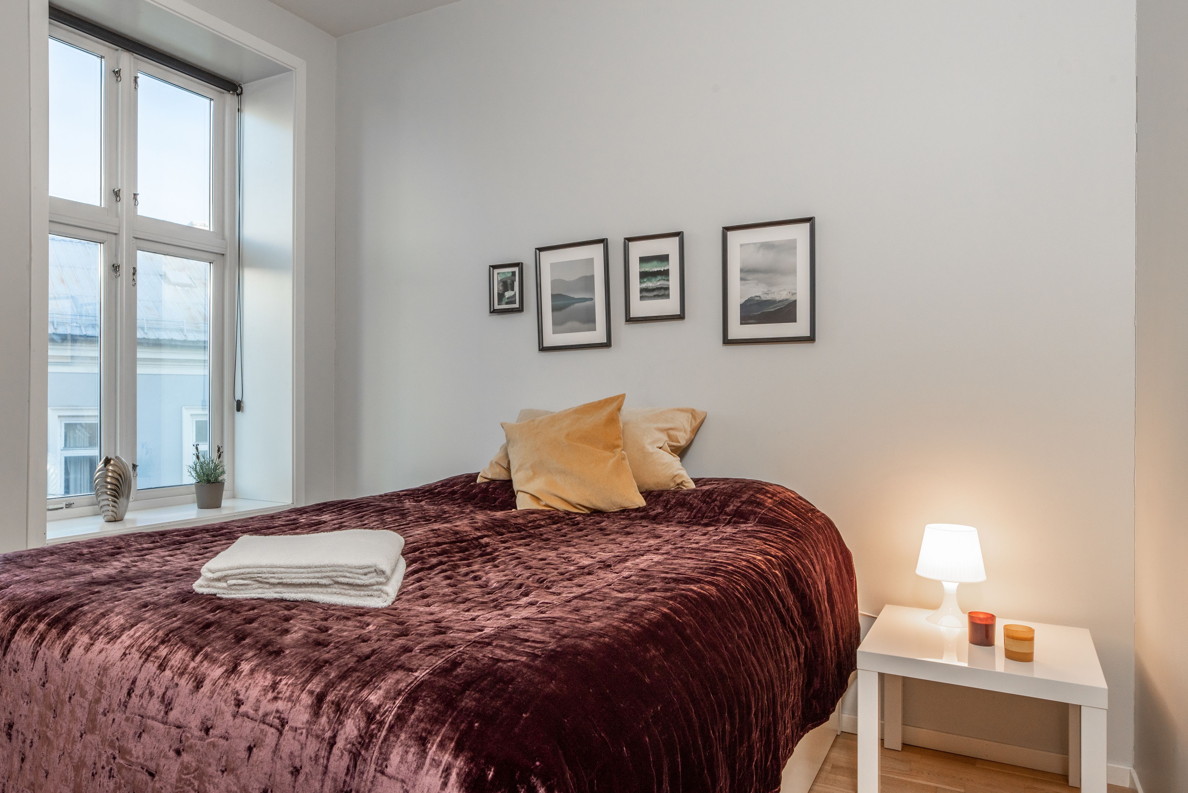 Une chambre à coucher avec un grand lit, une lampe de chevet et des tableaux encadrés accrochés au mur.