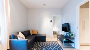 Ein modernes Wohnzimmer mit einer Eckcouch, einem Flachbildfernseher und einem Couchtisch.