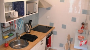 A compact kitchen with a wooden countertop, stainless steel sink, and a small dining area with a chair and table. - 70's Hostel (Mafra)