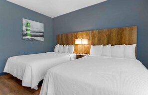A hotel room with two beds, a wooden headboard, a nightstand with a lamp, and a painting of a lighthouse. - Extended Stay America Premier Suites Phoenix Chandler Downto (Chandler)
