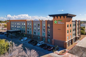 Ein Stay America Hotel mit mehreren Etagen, einem Parkplatz und blauem Himmel.