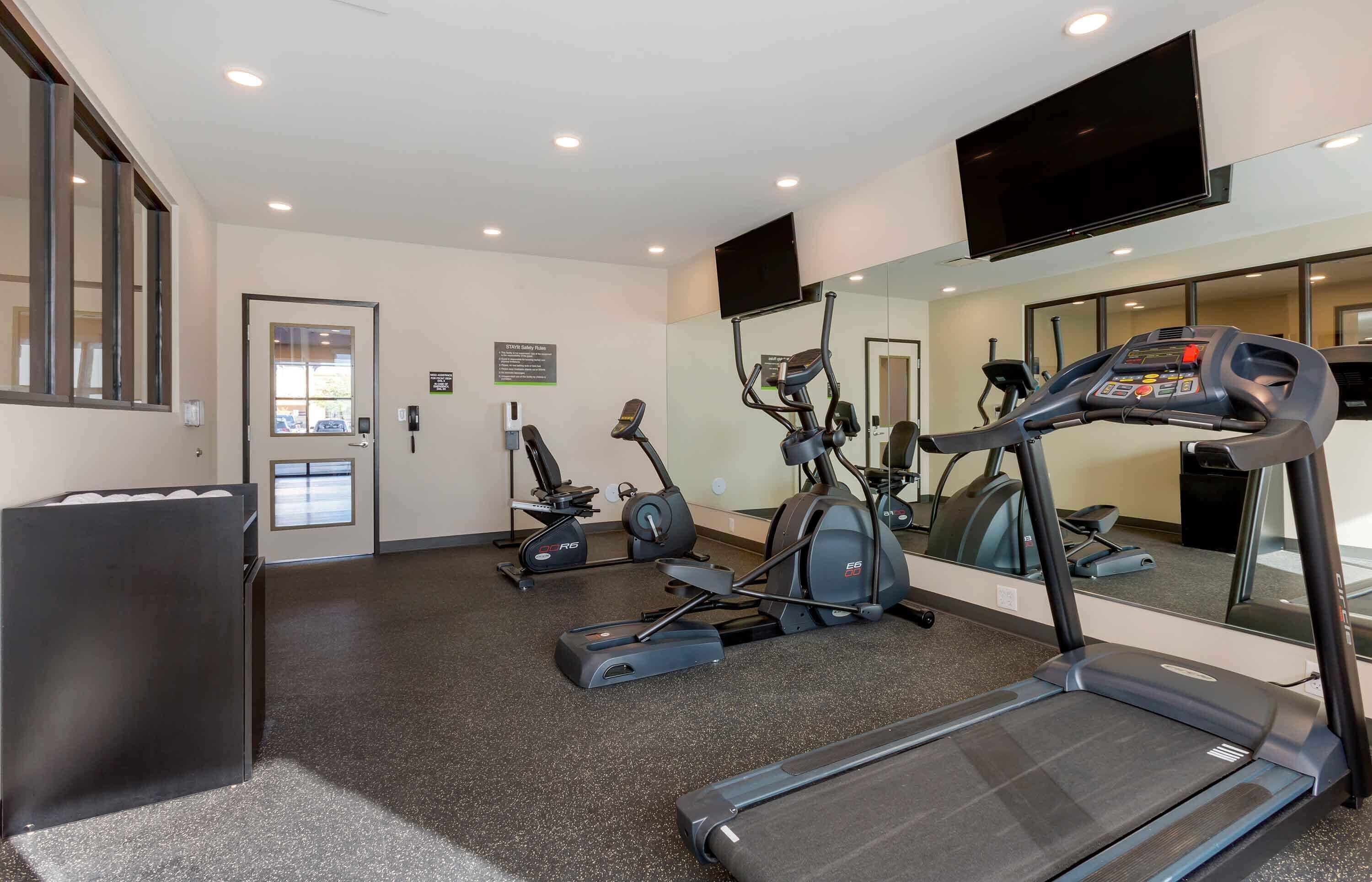 Une salle de sport équipée de tapis de course, de vélos elliptiques et d’un vélo d’appartement.