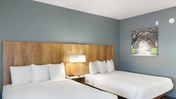 Ein Hotelzimmer mit zwei Betten, einem Holz-Kopfteil, einem Nachttisch mit Lampe und einem Bild an der Wand.