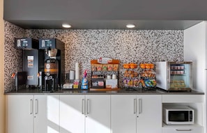 Una kitchenette equipada con cafetera, microondas y diversos alimentos.
