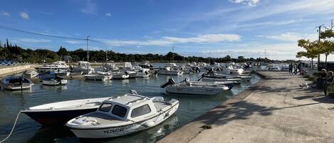 Un puerto deportivo con numerosos barcos amarrados a lo largo de una pasarela de hormigón.