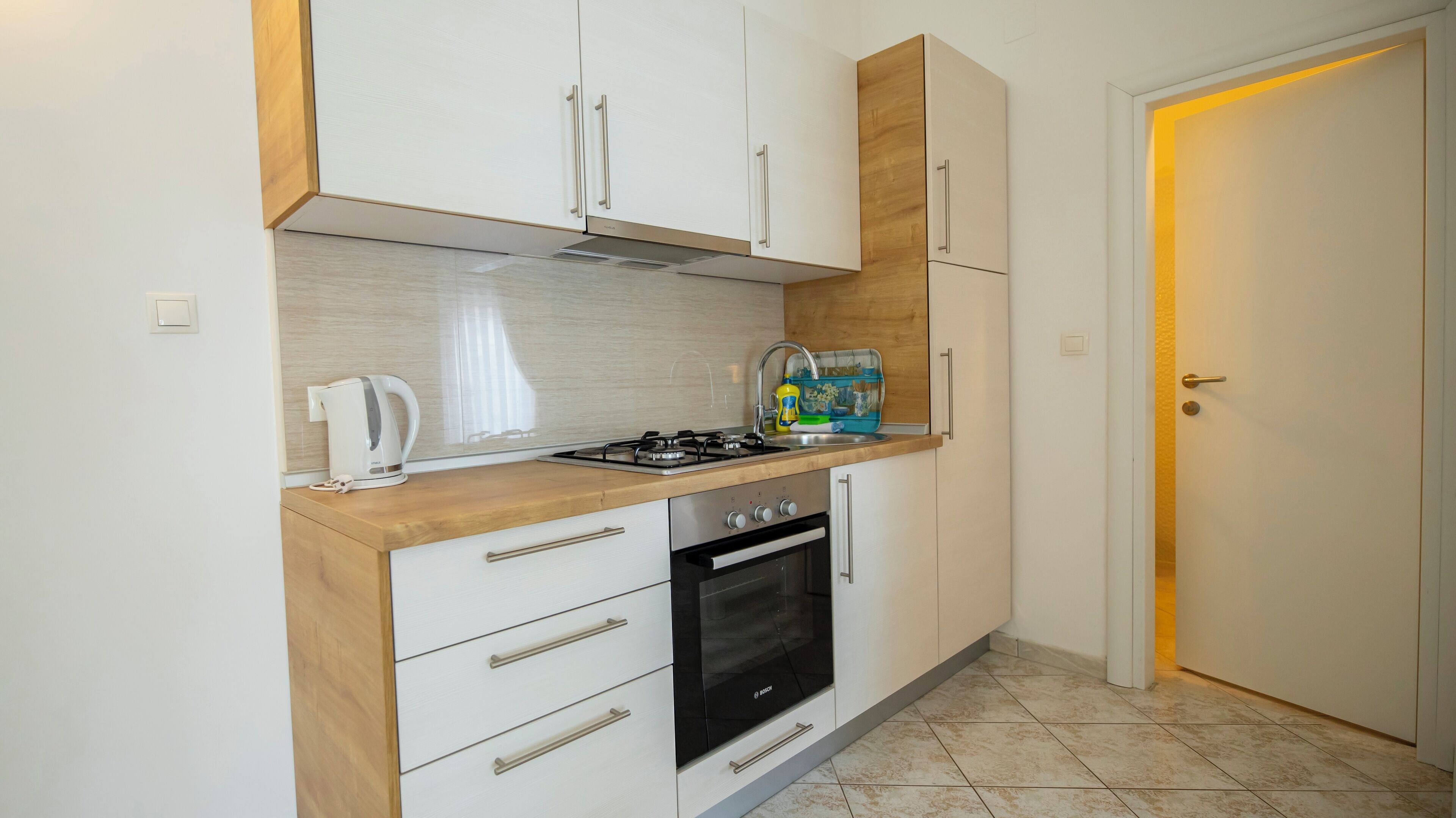 A compact kitchen with white cabinets, a Bosch oven, and a gas stove.