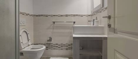 A modern bathroom with a toilet, sink, and shower area.