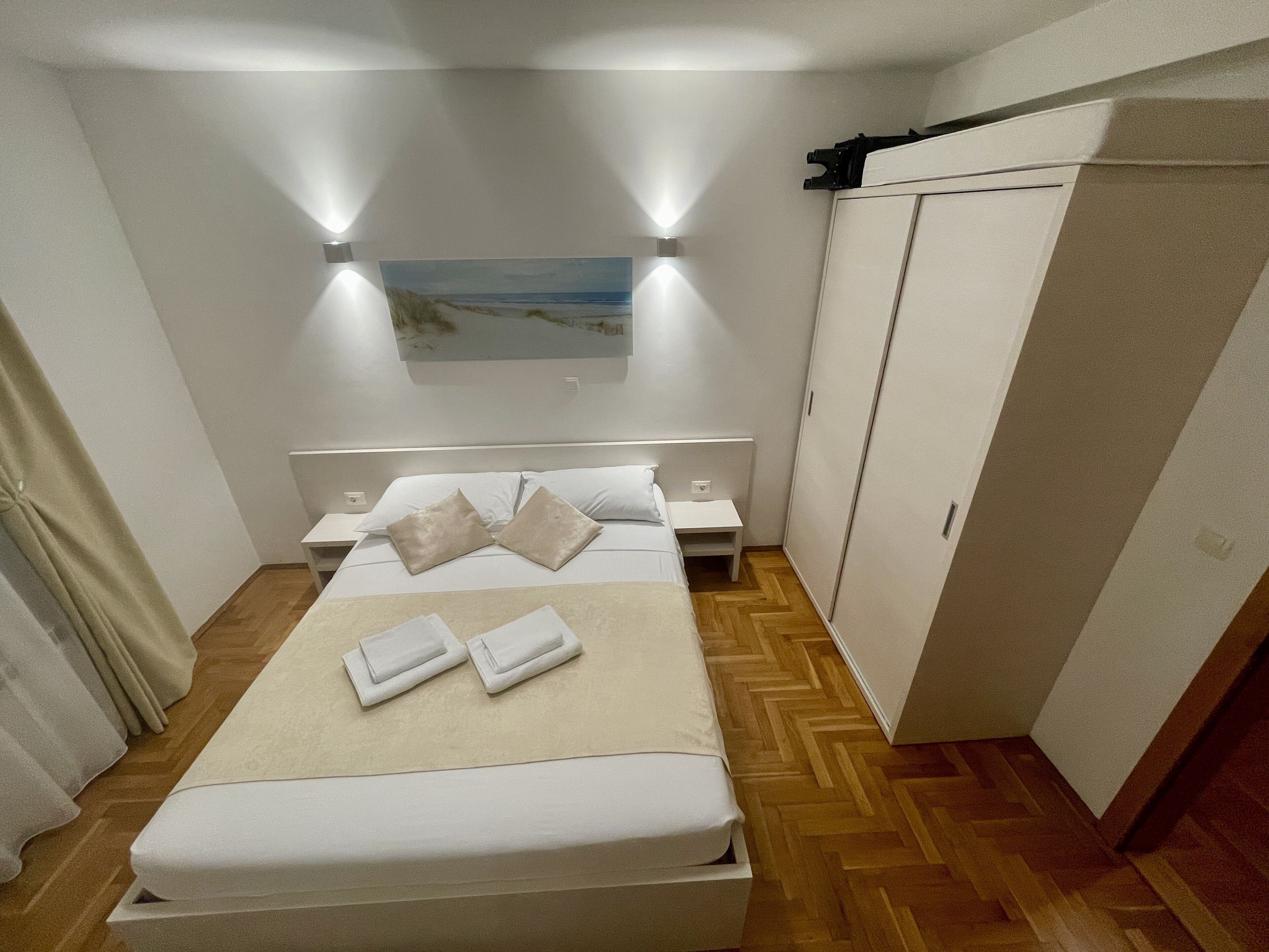 A bedroom with a bed, nightstands, a wardrobe, and a painting on the wall.