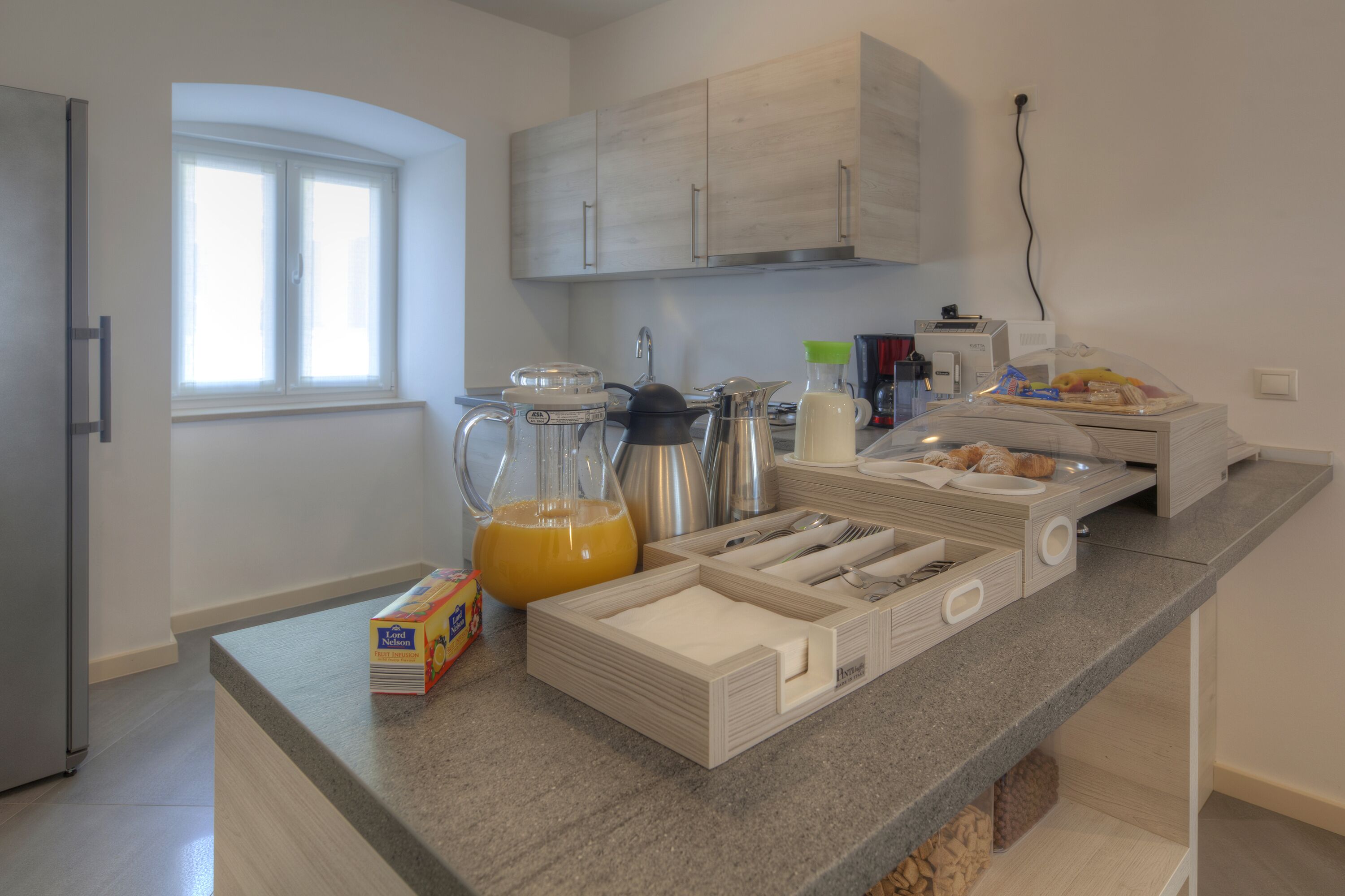 A modern kitchen with a granite countertop, built-in cabinets, and a window providing natural light.