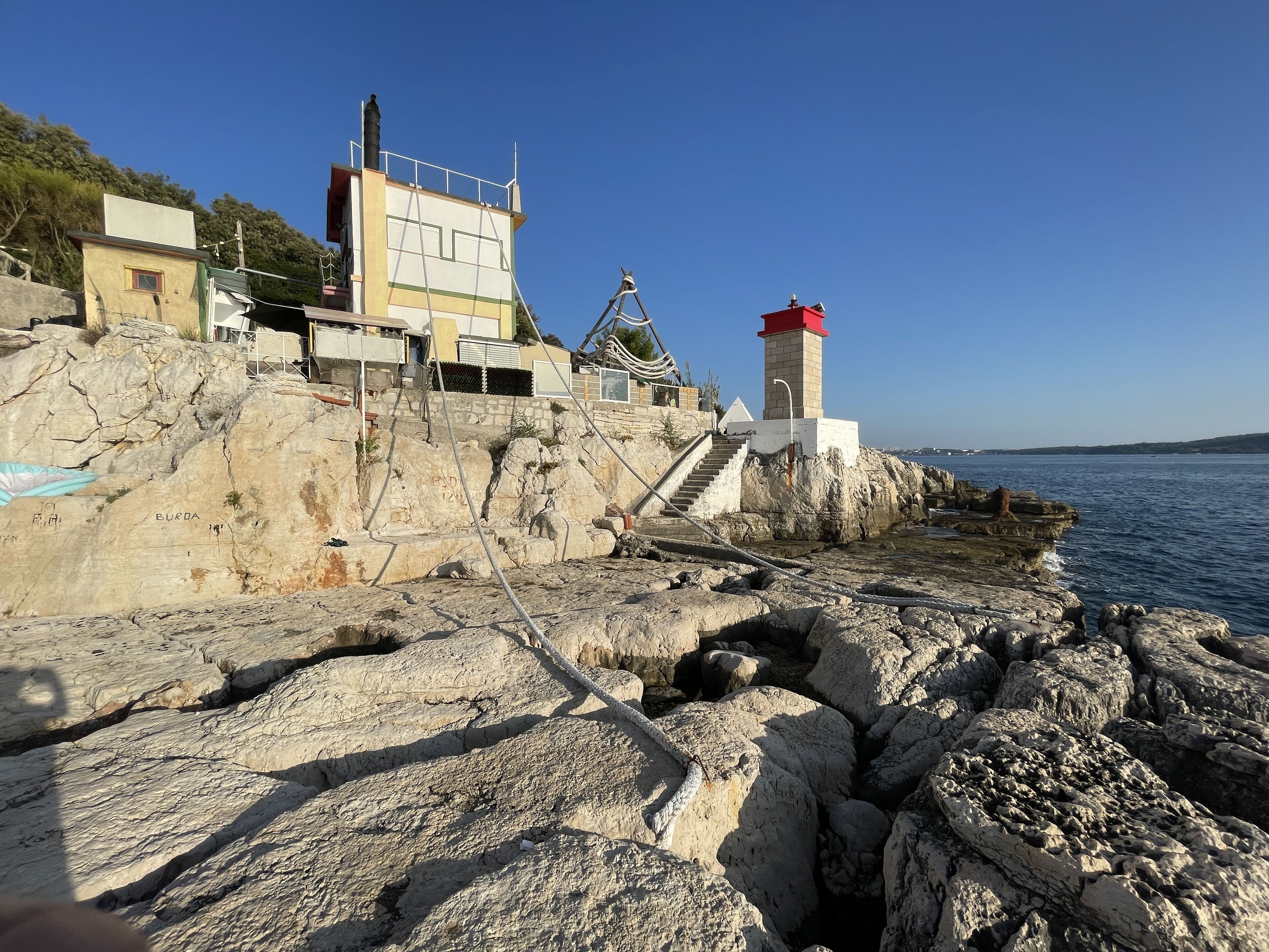 Un bâtiment situé sur la côte, doté d’un phare, entouré d’un terrain rocheux et offrant une vue dégagée sur la mer.