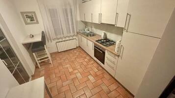 Una cocina compacta con alacenas blancas, estufa a gas, pileta y radiador.