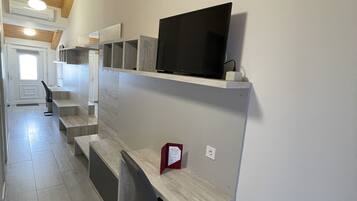 A modern interior with a wooden ceiling, built-in shelves, and a flat-screen TV.