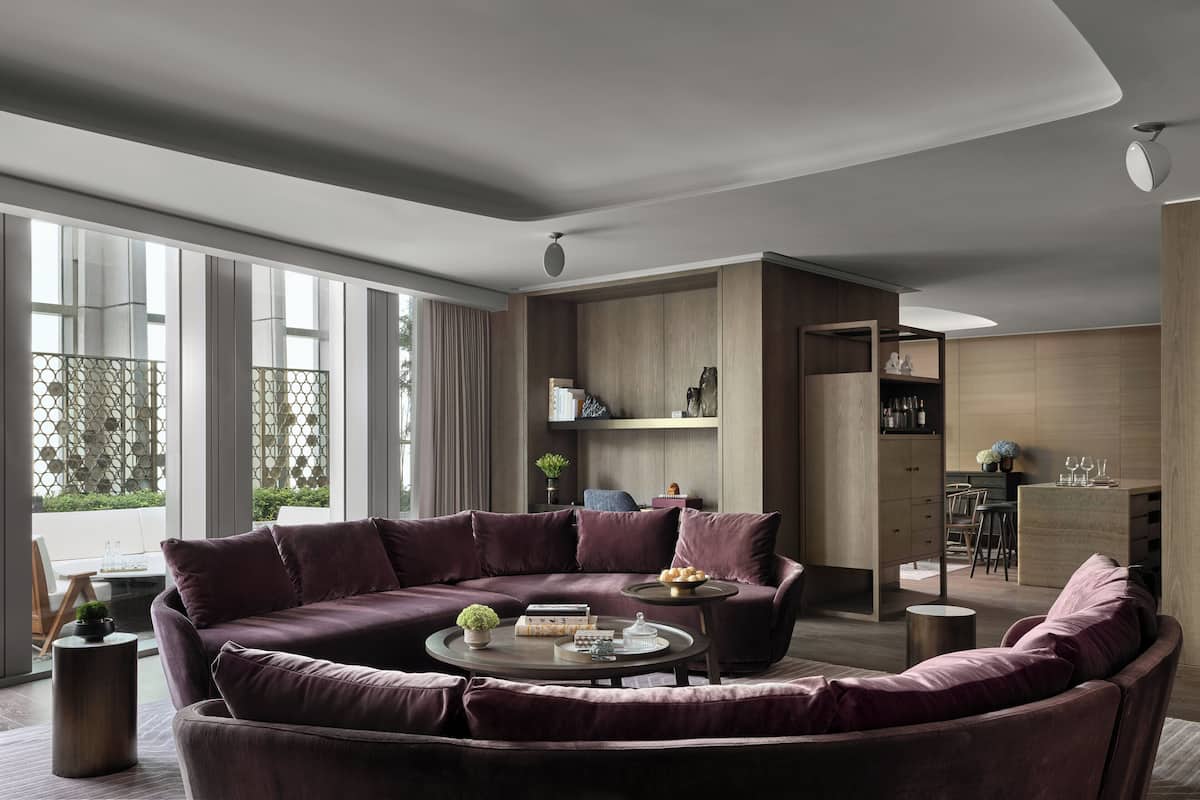 Una sala de estar moderna con un amplio sofá modular, una mesa de centro y un comedor con cocina al fondo.