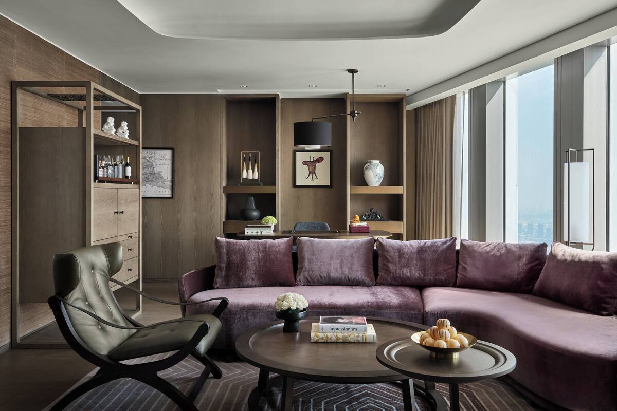 Una sala moderna con un sofá modular, un sillón de cuero, una mesa de centro y una estantería.