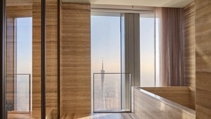 Ein modernes Interieur mit großem Fenster und Stadtblick, Holzboden und Glasgeländer.