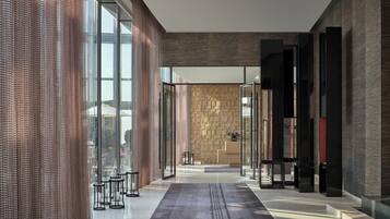A modern lobby with a glass partition, a patterned wall, and a reception desk.