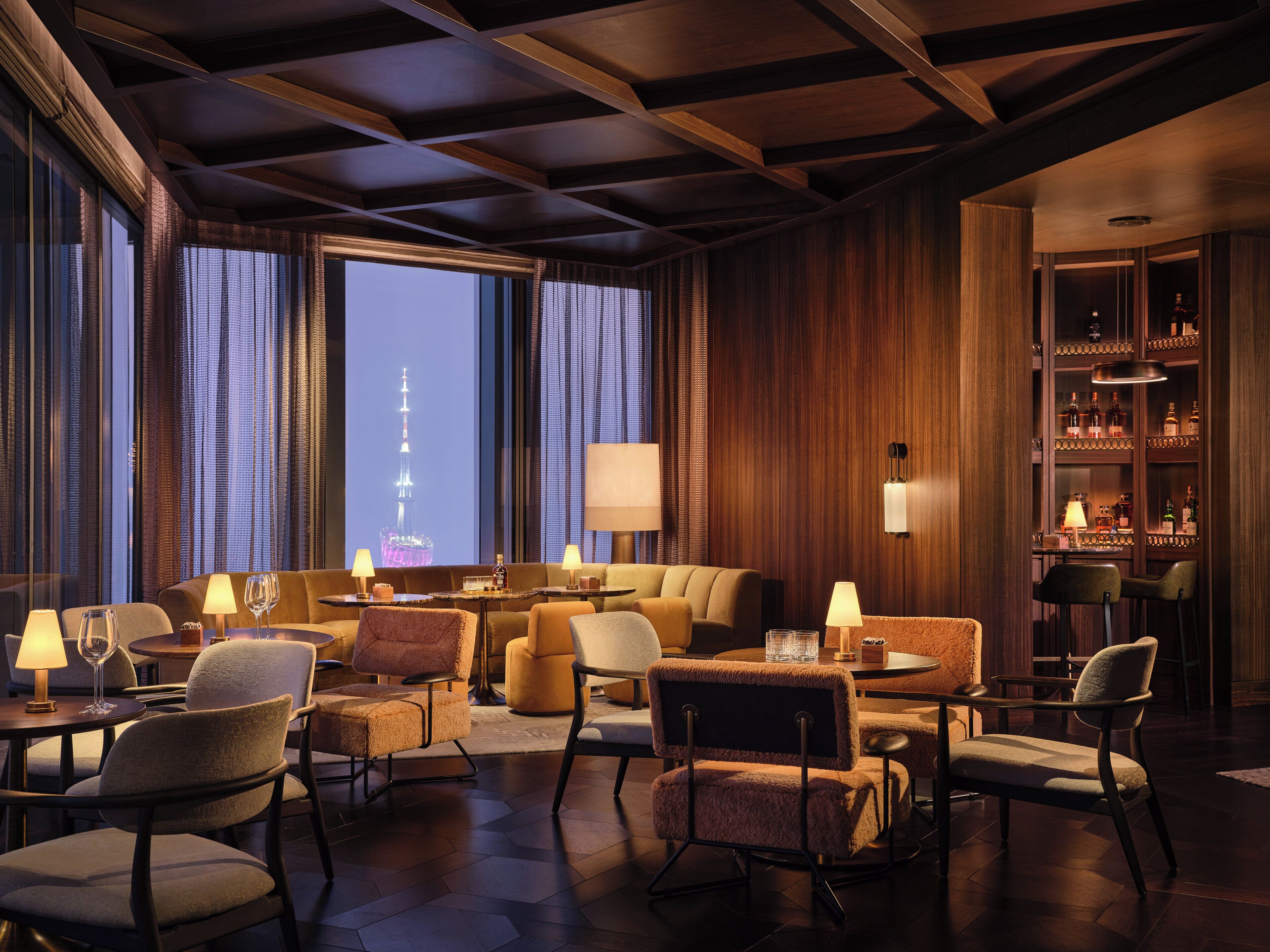 A hotel lobby with a view of a tower, plush seating, and a bar area.