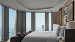 Ein modernes Hotelzimmer mit einem großen Bett, einem Nachttisch und Blick auf eine Stadtansicht, darunter ein hohes Gebäude.