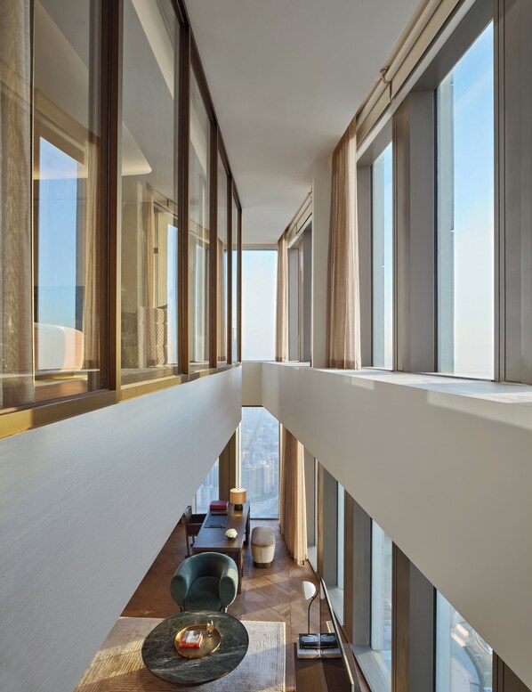 Un interior moderno con un largo pasillo, ventanas amplias y vistas a un paisaje urbano.