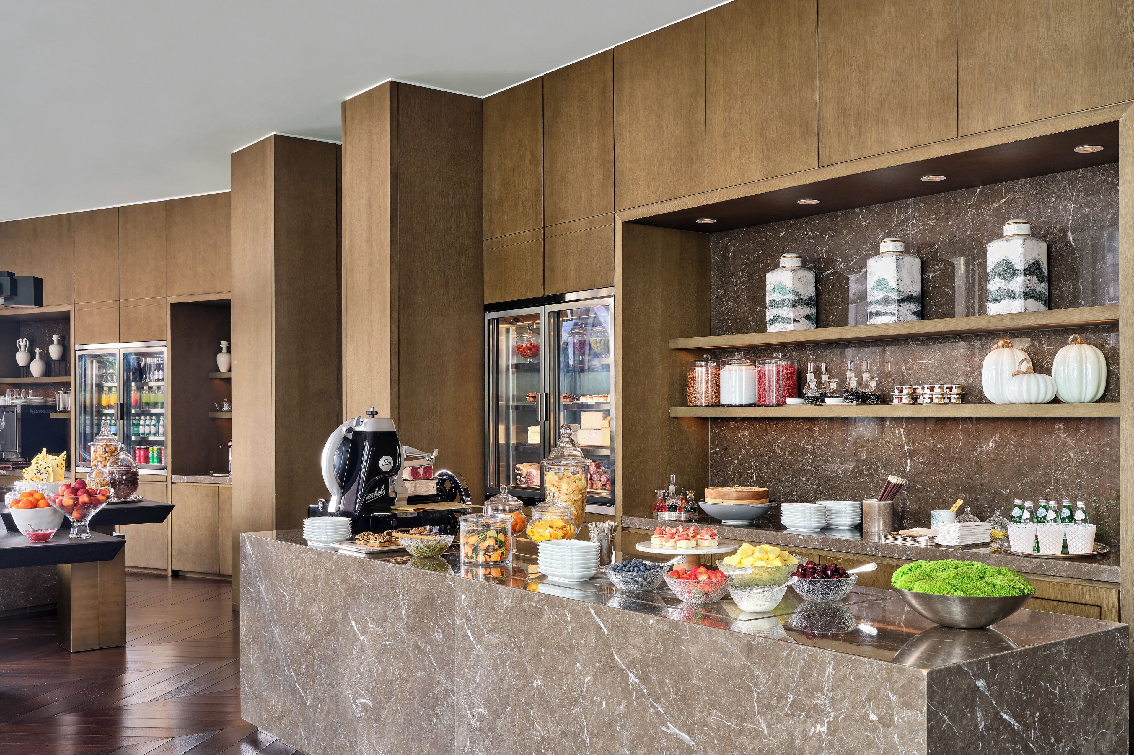 A buffet area with a marble counter, various food items, and decorative jars.