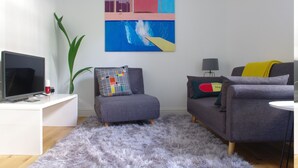 A modern living room with a grey sofa, a white coffee table, a flat-screen TV, and a large abstract painting on the wall. - The London Agent Chelsea Peaceful (London)