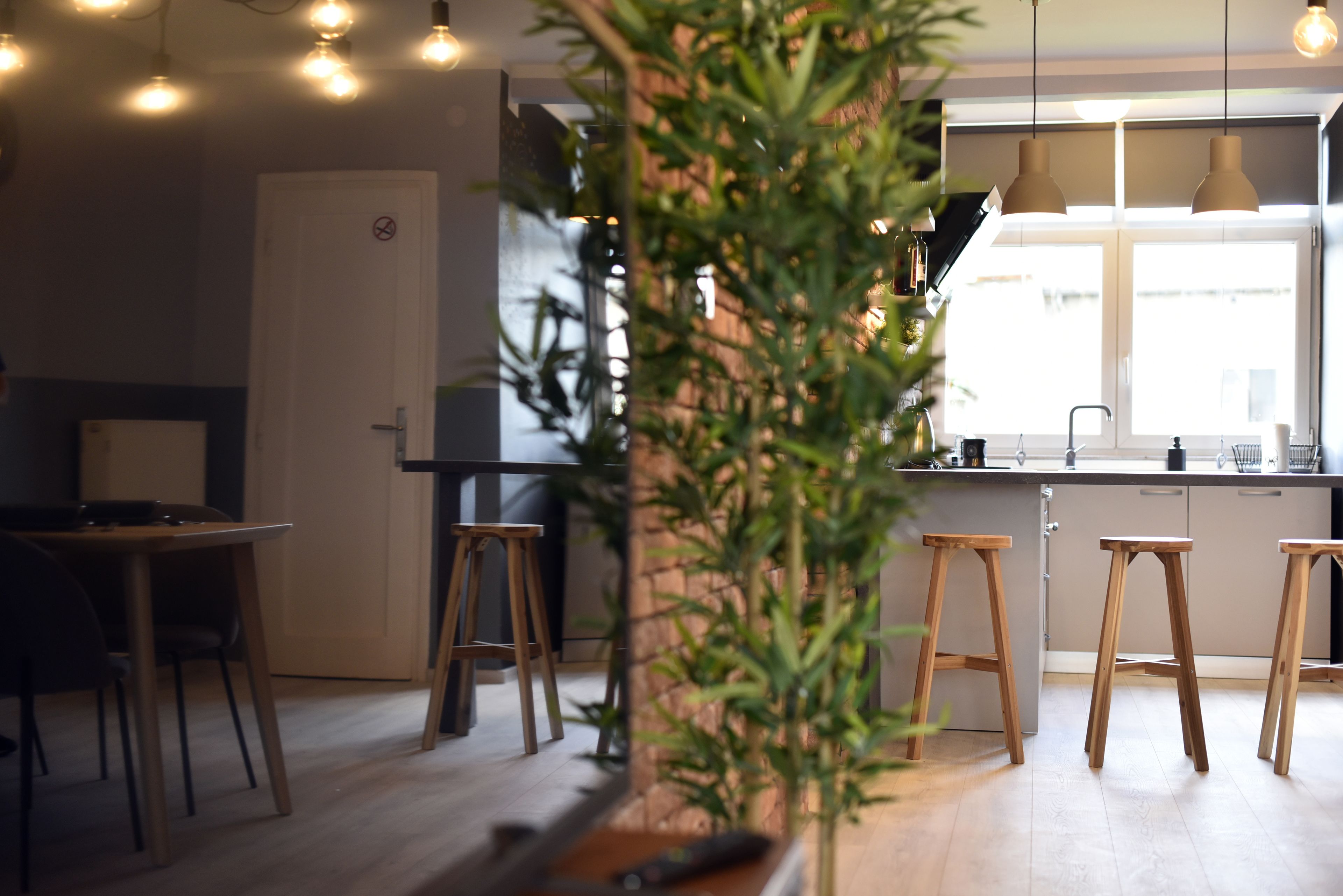 Une cuisine moderne avec des tabourets en bois, une table à manger et des luminaires suspendus.