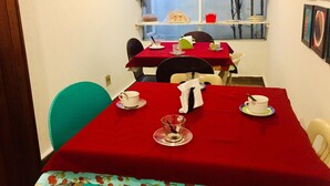 A dining area with red tablecloths, white chairs, and a window with a view of trees. - Hotel Cambará (Osasco)