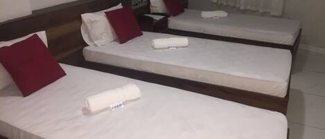 Une chambre d’hôtel avec deux lits simples, chacun étant équipé de draps blancs et d’oreillers rouges.
