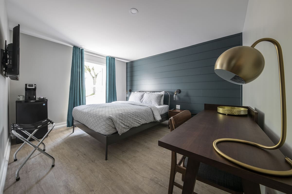 Ein modernes Schlafzimmer mit Bett, Nachttisch, Lampe und einer Kaffeemaschine.