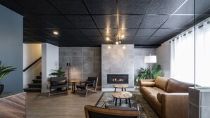 Een moderne woonkamer met een open haard, leren bank, houten salontafel en een trap naar een verdieping erboven.