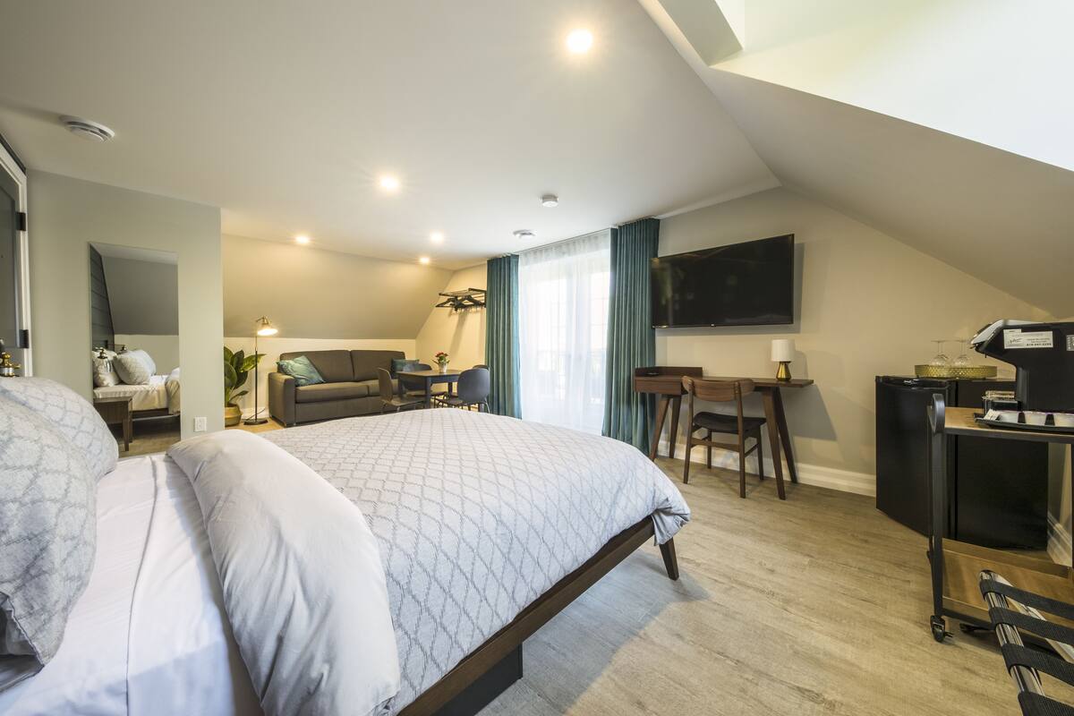 Ein modernes Schlafzimmer mit einem großen Bett, einem Schreibtisch und einem Fernseher.