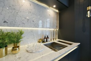 A modern kitchen with a marble backsplash, stainless steel sink, and gold accents.
