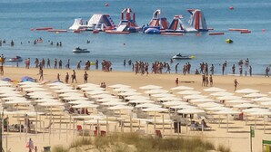 Una spiaggia con molti ombrelloni e persone.
