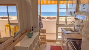 Una cucina con vista sulla spiaggia, un'area pranzo con sedie gialle e un tappeto rosso.