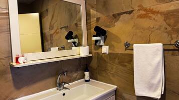 Un baño con lavamanos blanco, un espejo, toallero y artículos de aseo.