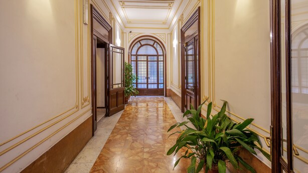 A hallway with a marble floor, arched windows, and wooden doors. - Domus Veneto Rome (Rome)