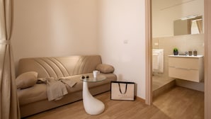 A modern living room with a beige sofa, a glass coffee table, and a Gucci bag on the floor. - Domus Veneto Rome (Rome)
