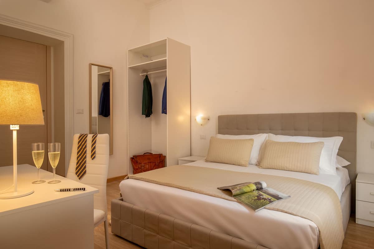 Ein Hotelzimmer mit Bett, Nachttisch, Lampe und Spiegel.