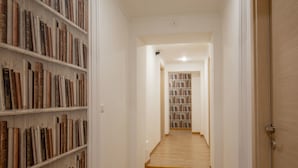 A narrow hallway with wooden flooring and white walls, leading to a room with a bookshelf. - Domus Veneto Rome (Rome)