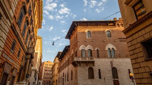 A narrow street with historic buildings, including a prominent brick building with arched windows and a balcony. - Domus Veneto Rome (Rome)