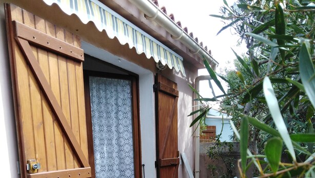 A wooden door with a patterned curtain, a metal chair, and a tiled patio. - Single room 2 person motel 2 (Porto-Vecchio)